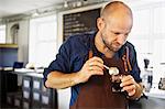 Male barista stirring coffee glass in coffee bar