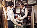 Father and son looking at fabric in family tailors shop