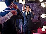 Young man trying on suit in traditional tailors shop