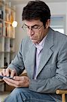 Mature man working at home texting on mobile phone