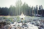 Mid adult woman practicing standing tree yoga pose in forest