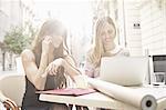 Two young female friends taking a break at sidewalk cafe, Valencia, Spain