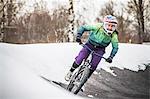 Young female mountain biker riding in snow