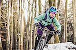 Female mountain biker riding through forest