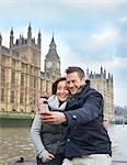 Mature tourist couple photographing selves and Houses of Parliament, London, UK