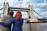 Mature tourist couple photographing Tower Bridge, London, UK