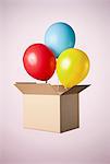 Studio shot of cardboard box with balloons coming out