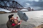 A young couple pose in front of the Forth Rail Bridge in Queensferry, near Edinburgh, Scotland