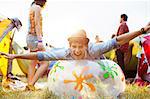 Portrait of playful man laying on inflatable chair outside tents at music festival