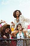 Cheering woman on man's shoulders at music festival