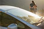 Couple hugging outside car at roadside