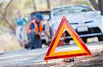 Warning triangle on road with mechanic in background