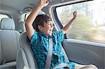 Enthusiastic boy cheering in back seat of car