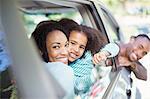 Portrait of happy family leaning out car windows