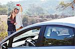 Couple taking self-portrait with cell phone outside car