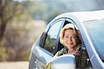 Portrait of confident senior woman leaning out car window