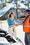 Woman shaking hands with roadside mechanic