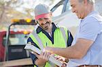 Man signing paperwork for roadside mechanic