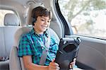 Happy boy using digital tablet in back seat of car