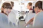 Portrait of happy brother and sister in back seat of car