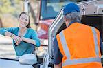 Grateful woman watching roadside mechanic fix car