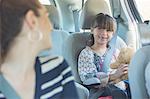 Mother turning and smiling at daughter in back seat of car