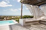 Curtains blowing in wind on luxury poolside patio overlooking ocean