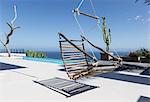 Hanging wooden chair on luxury patio overlooking ocean