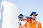 Worker carrying stainless steel tube near silage storage tower