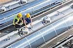 Workers on platform above stainless steel milk tanker