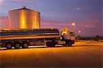 Stainless steel milk tanker parked next to silage storage tower at night