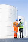 Businessman and worker using digital tablet next to silage storage towers