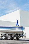 Worker walking on platform above stainless steel milk tanker