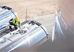 Worker on platform above stainless steel milk tanker