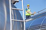 Worker using laptop on platform above stainless steel milk tanker