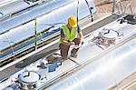 Worker using digital tablet on top of stainless steel milk tanker