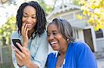 Mother and daughter looking at cell phone and laughing