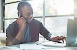 Businessman talking on cell phone and using laptop