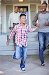 Father and son holding hands and running outside house