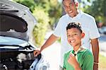 Portrait of smiling grandson repairing car engine with grandfather