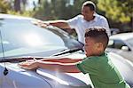 Grandfather and grandson wiping car