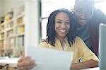 Portrait of happy couple with paperwork at laptop