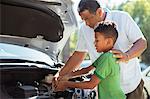 Grandfather and grandson repairing car engine