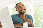 Happy man drinking coffee at laptop