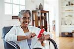 Happy senior woman text messaging with cell phone in living room