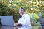 Senior man using laptop at patio table