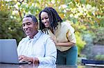 Father and daughter using laptop at patio table