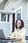 Portrait of smiling woman using laptop at patio table