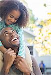 Close up of happy father carrying daughter on shoulders