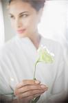 Close up of woman in bathrobe holding white rose